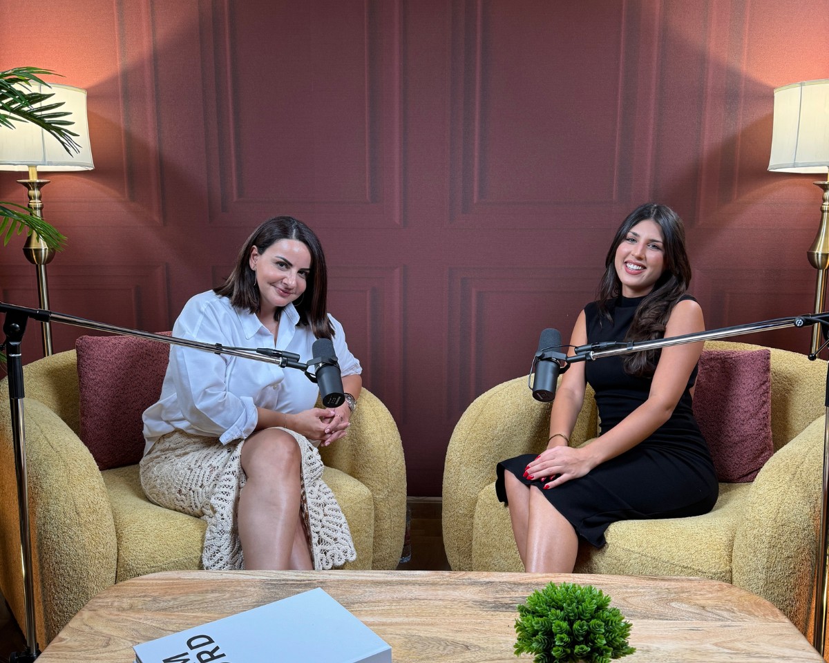 Two women recording a real estate podcast in a professional studio setting with microphones and seating